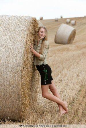 Beautiful blonde teen Carisha strips naked next to a round bale of hay on nudesceleb.com