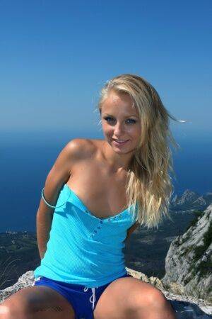 Blonde model Hella strikes great nude poses on a cliff high above the ocean on nudesceleb.com