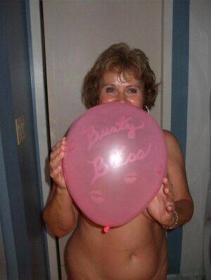 Mature lady models totally naked while playing with balloons on nudesceleb.com