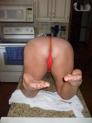 Older amateur Busty Bliss gets naked on a kitchen counter in a thong on nudesceleb.com