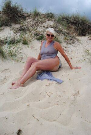 Mature platinum blonde Dimonty models at the beach in see through clothing on nudesceleb.com