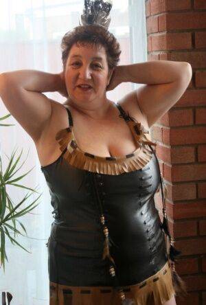 Sick mature woman Kinky Carol models leather lingerie in black boots on nudesceleb.com