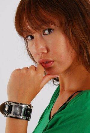 Redheaded Asian girl Evita models a Guess style cuff watch during SFW action on nudesceleb.com