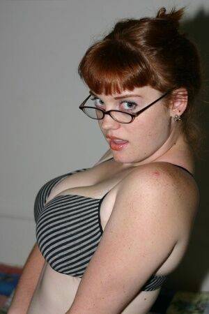 Redhead amateur Sawyer cups her natural breasts before removing her glasses on nudesceleb.com