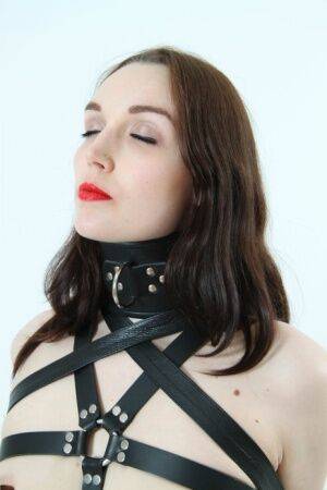 Beautiful girl models leather BDSM attire with her arms restrained behind her on nudesceleb.com