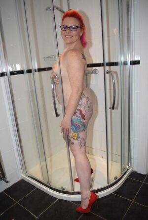 Tattooed redhead Mollie Foxxx models completely naked in a bathroom on nudesceleb.com