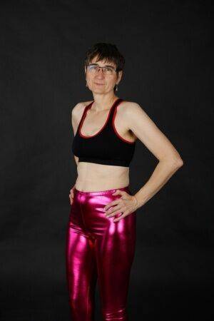 Mature woman models a sports bra in shiny pants and black boots on nudesceleb.com