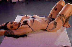 Tattooed chick Misha Montana models a skimpy bikini in a sexy manner on nudesceleb.com