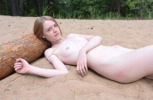 Skinny redhead Gerda models totally naked on a patch of sand in the woods on nudesceleb.com