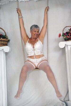 Short haired oma Savana models all white lingerie and hosiery on a swing on nudesceleb.com