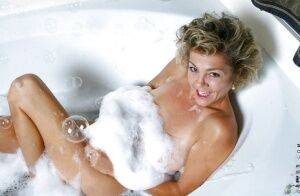 Tempting mature drinking wine and masturbating in a foamy bath tub on nudesceleb.com