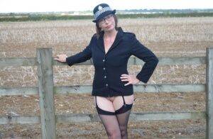 Mature policewoman Barby Slut removes her uniform against a fence at a farm on nudesceleb.com