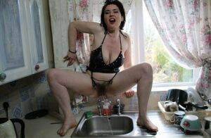 Amateur woman Juicey Janey squats over the kitchen sink for a piss on nudesceleb.com