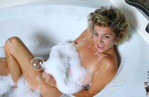 Mature lady soaks in a bathtub while toying her hairy pussy on nudesceleb.com