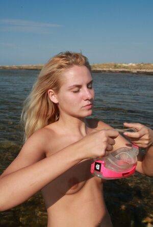 18-year-old blonde Agnes H poses nude in snorkeling gear in shallow water on nudesceleb.com