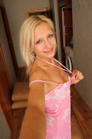 Natural blonde Nastya takes self shots while getting naked in a hallway on nudesceleb.com