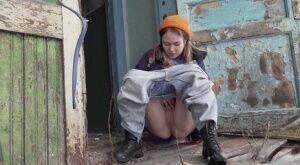 Cute girl pulls down jeans for an urgent piss on the steps of an old building on nudesceleb.com