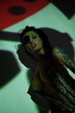 Solo girl Christy Mack wears an eye patch and lingerie while posing in shadows on nudesceleb.com