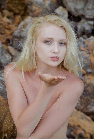 Blonde solo girl Nika N blows a kiss while posing nude on rusty boulders on nudesceleb.com