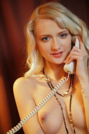 Sweet blonde teen Nika N answers the telephone while wearing a garter belt on nudesceleb.com