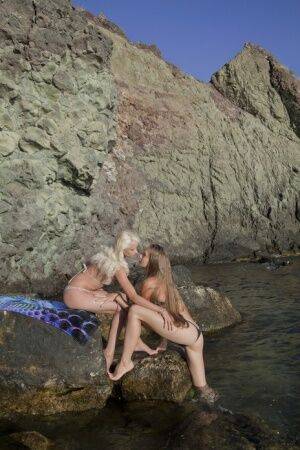 Against the wet and rugged landscape of a river, Nika and Milena makes a on nudesceleb.com