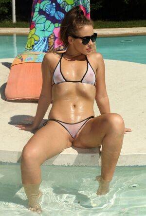 Hot Emma Brown peels her bikini to stuff a glass in her spread pussy poolside on nudesceleb.com