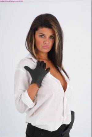 Clothed woman Claire lets a breasts escape a white shirt in leather gloves on nudesceleb.com