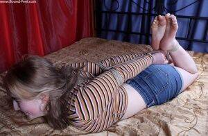 White girl is left on a bed while hogtied in a long sleeved shirt and cutoffs on nudesceleb.com