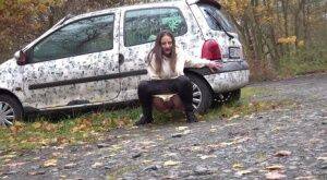 White girl Nicolette Noir takes a piss beside a parked car in a wooded setting on nudesceleb.com