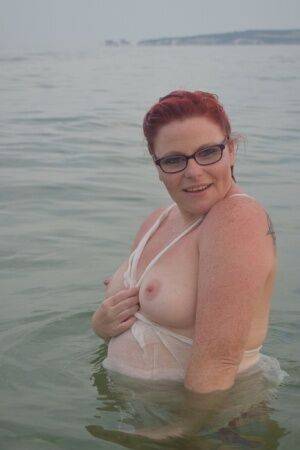 Tattooed redhead poses nude on a beach before masturbating on a toilet seat on nudesceleb.com