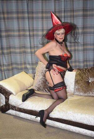 Older blonde removes a red velvet dress pose nude in a witch's hat and hosiery on nudesceleb.com