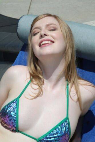 Pale blonde hottie with natural tits Dolly Leigh fools around at the pool on nudesceleb.com