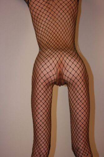 Solo model with a shaved head poses in a fishnet bodystocking on nudesceleb.com