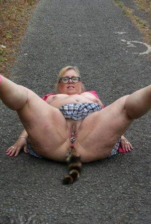 Fat UKwoman Lexie Cummings walks a path sporting a raccoon tail butt plug on nudesceleb.com