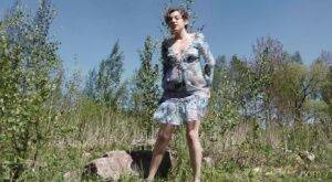 Clothed woman Sasha S hitches up her dress to take a pee on a rock on nudesceleb.com