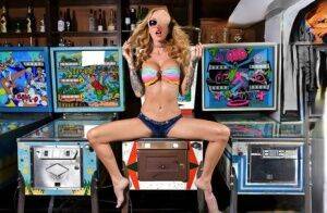 Inked chick Sarah Jessie toys her pussy atop a pinball machine while alone on nudesceleb.com