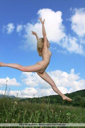 Flexible blonde teen Thea C juggles while completely naked in a field on nudesceleb.com