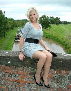 Blonde female sits atop a bridge in a dress and nylons with shiny pumps on nudesceleb.com