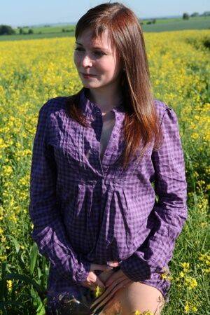 Young redhead gets completely naked in a field of Rapeseed on nudesceleb.com